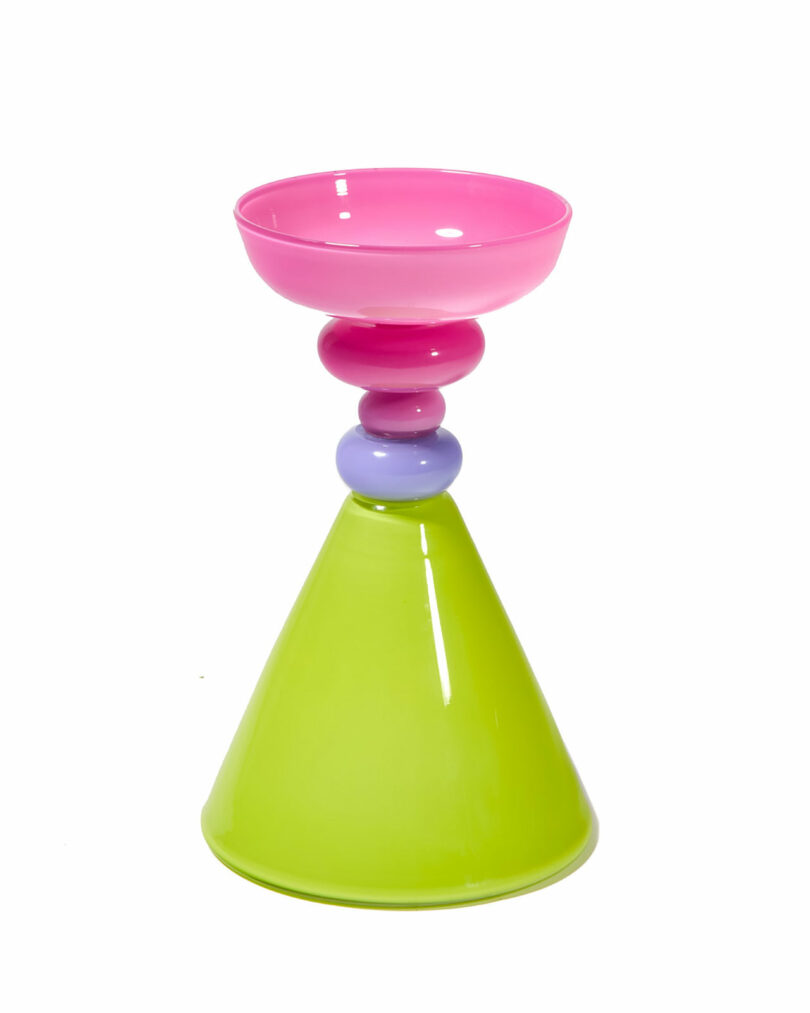 A colorful object with a wide green cone-shaped base, two round beads in pink and purple, and a pink bowl on top.