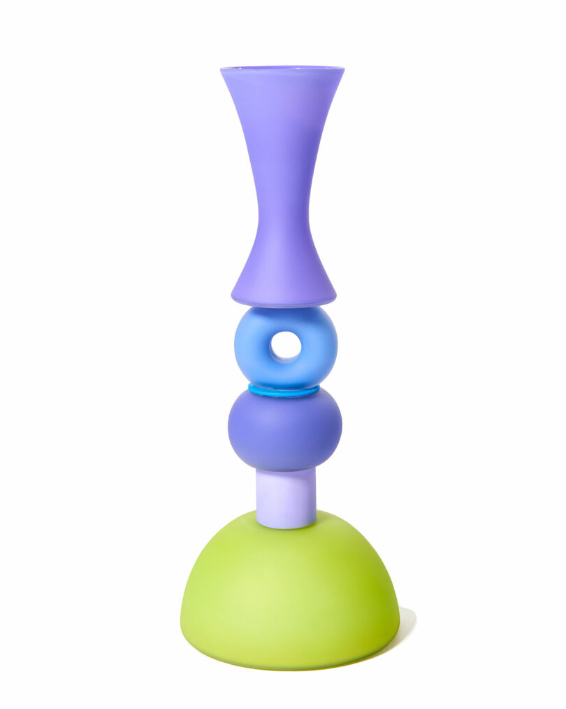 A modern, abstract vase with stacked geometric shapes in purple, blue, and green, set against a white background.